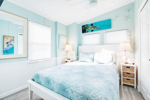 a bedroom with a bed with blue walls and windows at OCEANIA... water front cottage retreat ~ in Cudjoe Key