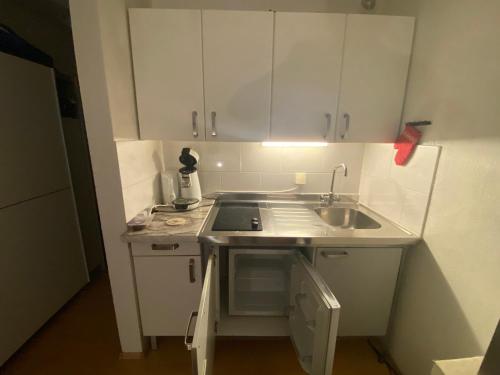 una pequeña cocina con armarios blancos y fregadero en Appartement Altstadt Mainz, en Mainz