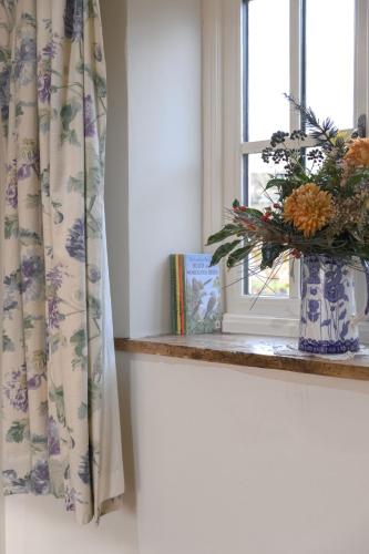 a window with a vase of flowers on a window sill at The Rear of the Plough,Everdon. in Daventry