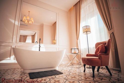 a bathroom with a tub and a chair and a mirror at Vili Apartments in Oradea