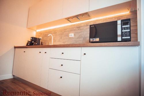a kitchen with white cabinets and a microwave on a counter at Vili Apartments in Oradea