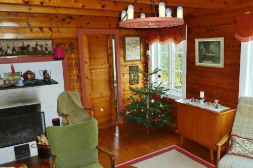 a living room with a christmas tree in a cabin at Alone In The Woods With Your Own River Nearby in Fitjar