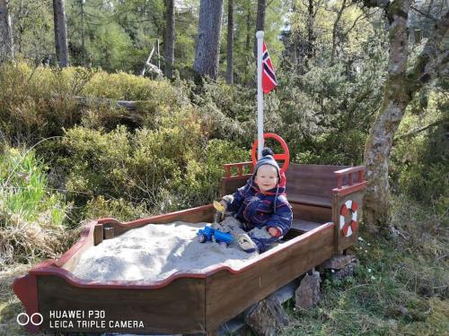 a small child sitting in a toy train with a flag at Alone In The Woods With Your Own River Nearby in Fitjar