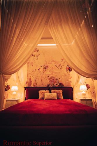 a bedroom with a red bed with curtains at Vili Apartments in Oradea