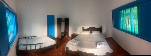 a bedroom with two beds and two windows at Finca del Rio Palomino in Palomino