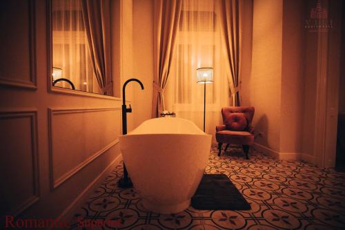 a bathroom with a tub in a room with a chair at Vili Apartments in Oradea