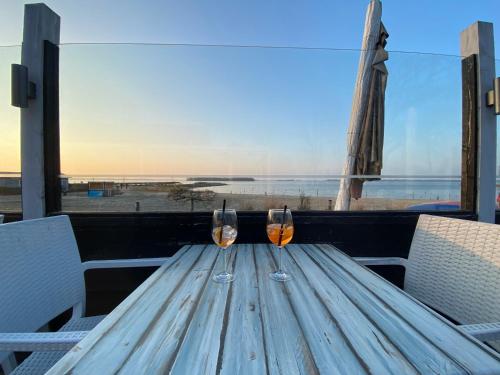 two wine glasses sitting on top of a wooden table at GREEN VILLA in bester Lage - Dachterrasse mit Meerblick - großer eingezäunter Garten - kinderfreundlich - Hunde inklusive - 4 Sterne Resort - direkt am Strand - Pool inklusive in Hulshorst