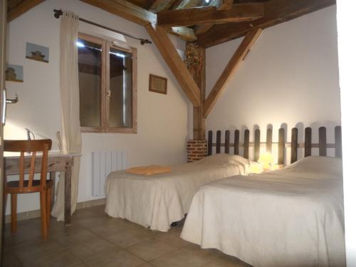 a bedroom with two beds and a window and a chair at gite de la jument grise in Lescheroux