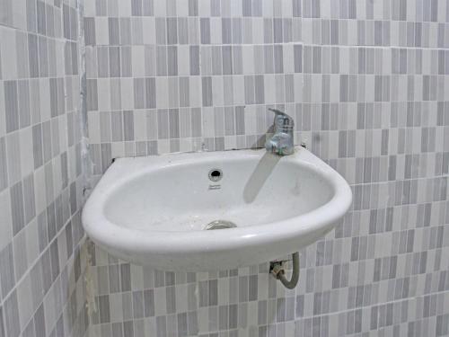 ein weißes Waschbecken im Bad mit grauen Fliesen in der Unterkunft OYO 92059 Archi Homestay in Lembuak