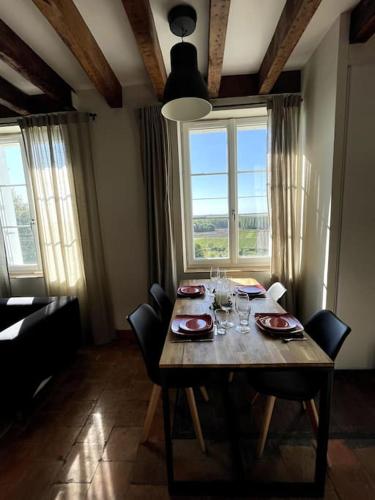 une table de salle à manger avec des chaises et une grande fenêtre dans l'établissement Le Petit Nice Maison semi-troglodyte de charme., à Vouvray