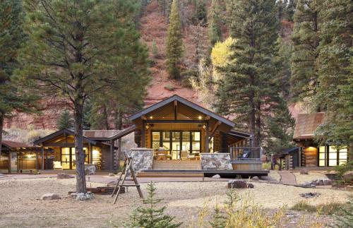 a large wooden house in the middle of a forest at Slippery Rock River Ranch in Dolores