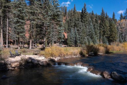 a river with a bench next to a forest at Slippery Rock River Ranch in Dolores