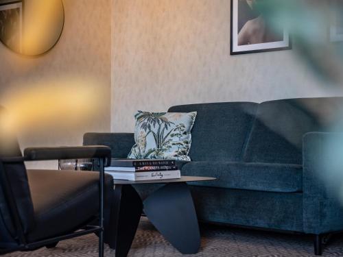 a living room with a blue couch and a table at Quality Hotel Prinsen in Trondheim