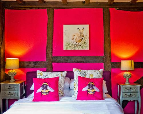 Schlafzimmer mit rosa Wänden und einem Bett mit rosa Kissen in der Unterkunft Ye Olde Smugglers Inne in Alfriston