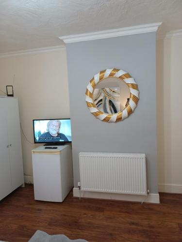 a room with a television and a mirror on the wall at Gabriel Guesthouse in Rhyl