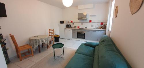 a living room with a green couch and a kitchen at Gîte Caves de Beauval (à 100m du zooparc !) in Saint-Aignan