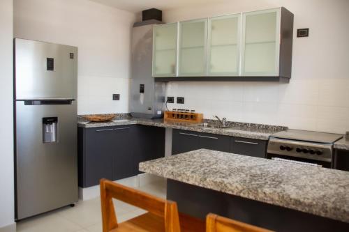 La cuisine est équipée de placards gris et d'un réfrigérateur en acier inoxydable. dans l'établissement Dpto de 2 dorm, en el corazón de la ciudad, à San Fernando del Valle de Catamarca