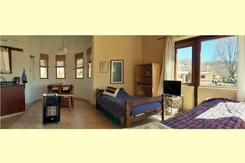 a bedroom with two beds and a table and a kitchen at CabañaPerchel Tilcara Quebrada de Humahuaca in Huacalera