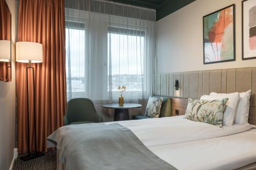 a hotel room with a bed and a table and window at Quality Hotel Prinsen in Trondheim