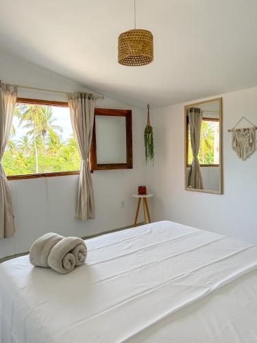 - une chambre blanche avec un grand lit blanc et des fenêtres dans l'établissement Casa Al Mare Preá, à Prea