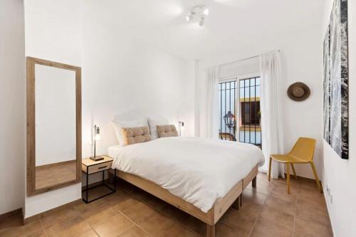a white bedroom with a large bed and a mirror at Luxe appartement, centrum Marbella, vlak aan zee! in Marbella