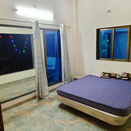 een slaapkamer met een paars bed en een raam bij Shobhnath Home Stay in Harnai