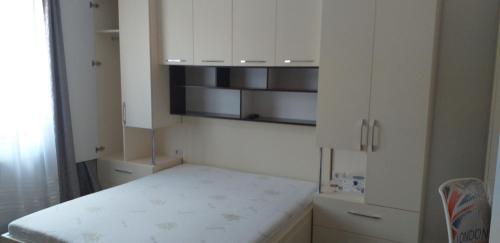 um quarto branco com uma cama e armários brancos em Apartament lux em Roman
