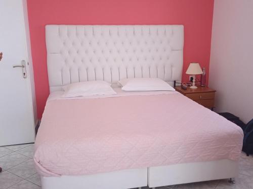 a bedroom with a white bed and a red wall at Pension Ptolemeos in Fira