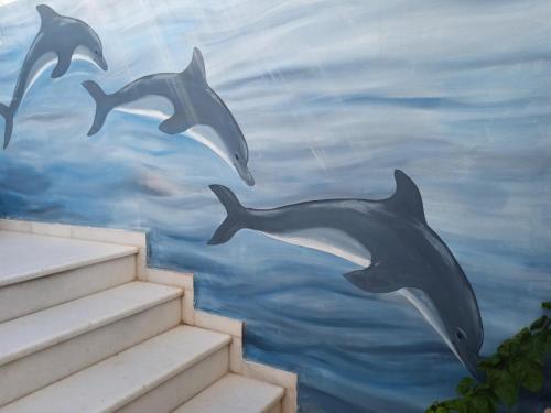 una pintura de delfines saltando del agua en Pension Ptolemeos, en Fira