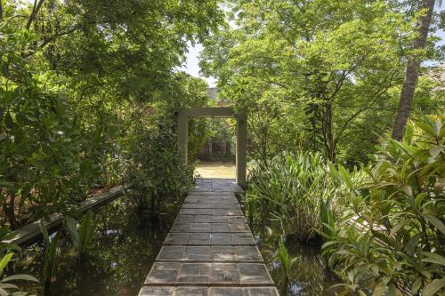 a walkway through a garden with trees and water at Ayana Sea in Wadduwa