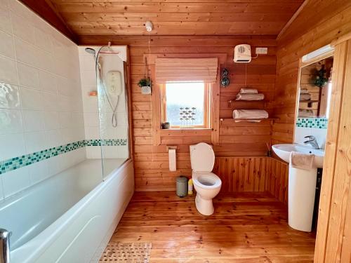 a bathroom with a toilet and a tub and a sink at Lake Pochard, Oak Lodge in South Cerney