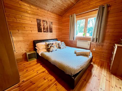 a bedroom with a bed in a wooden room at Lake Pochard, Oak Lodge in South Cerney