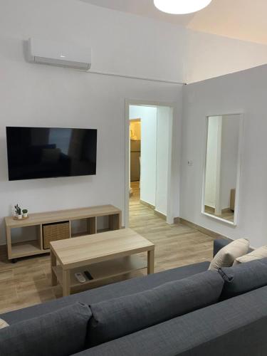 a living room with a blue couch and a tv at Casas La Aldea Suites Plaza in La Aldea de San Nicolas