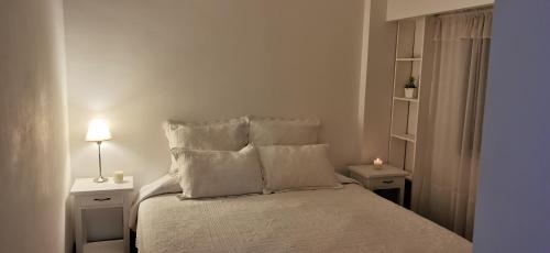 um quarto com uma cama com lençóis brancos e almofadas em Teodoro's Home em Buenos Aires