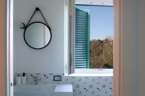 ein Bad mit einem Spiegel, einem Waschbecken und einem Fenster in der Unterkunft La Casa del Bosco - Unique two storey House with garden in Neapel