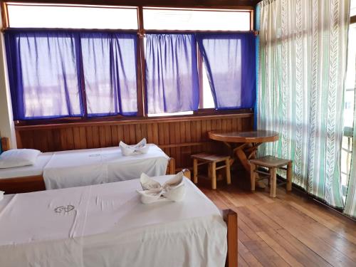 a room with two beds and a table and windows at Hotel Boutique Hurvínek in Montañita