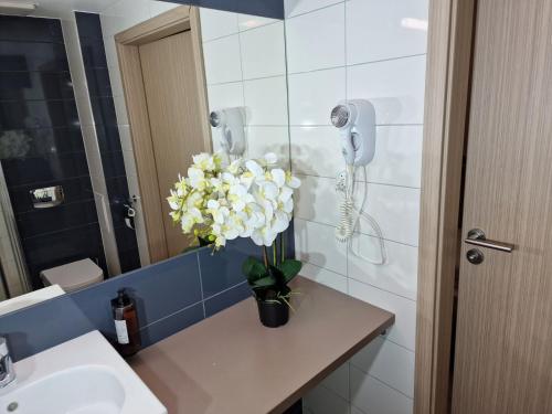 a bathroom with a sink and a vase of flowers at AGAT Apartament Czarna Góra in Sienna