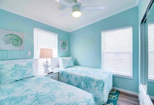 two beds in a bedroom with blue walls and windows at NAUTILUS...ocean front cottage retreat ~ in Cudjoe Key