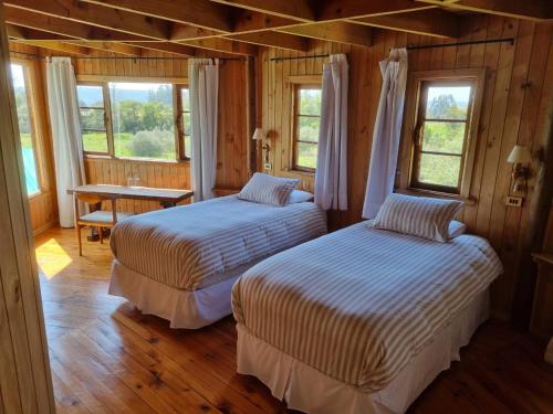 two beds in a room with a table and windows at B&B Casa Redonda in Santo Domingo