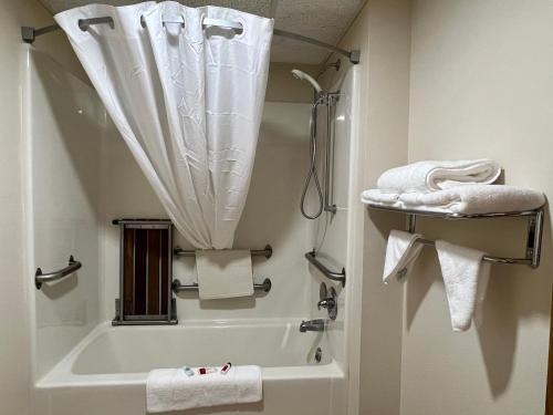 y baño con bañera, ducha y toallas. en Reston Inn & Suites, en Spencer