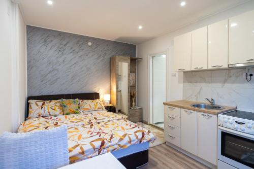 a bedroom with a bed and a kitchen with a sink at Apartments Solar Trebinje in Trebinje