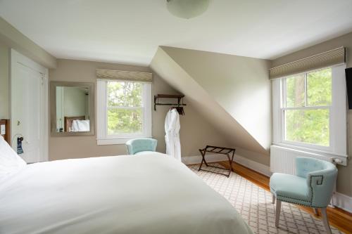 a bedroom with a white bed and two chairs at Lakehouse Inn in Lee