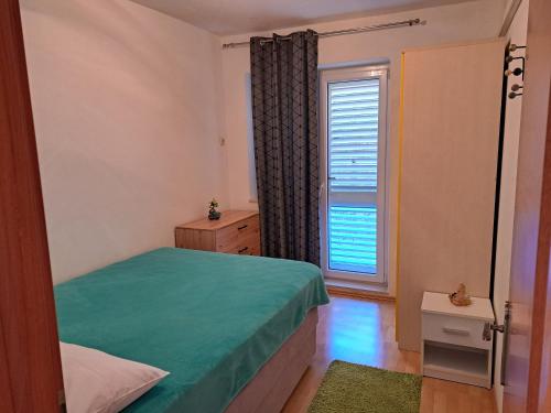 Un dormitorio con una cama verde y una ventana en Mateo, en Dugi Rat