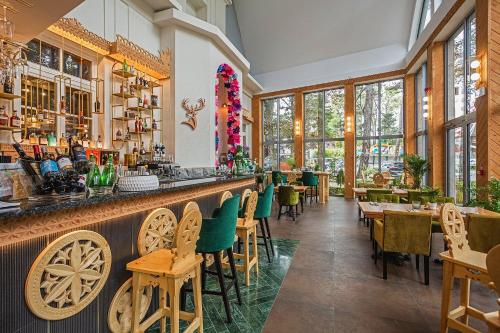 Un restaurante con un bar con sillas y mesas verdes. en Willa Monte, en Zakopane