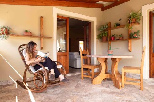 a woman sitting in a chair reading a book at Casa Pilighitta penthouse in Dorgali