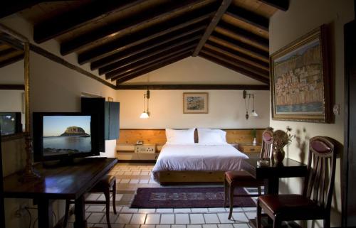 a bedroom with a bed and a flat screen tv at Lazareto Hotel in Monemvasia