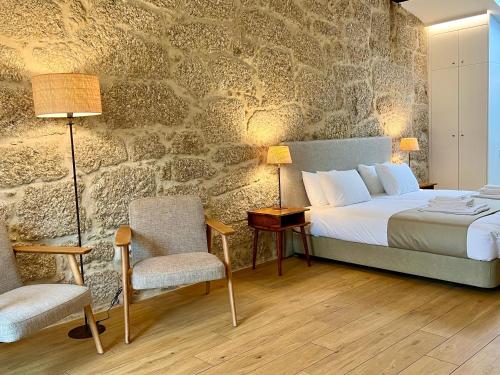 - une chambre avec un lit et un mur en pierre dans l'établissement Quinta da Porta - Solar de Vale de Prazeres, à Vale de Prazeres
