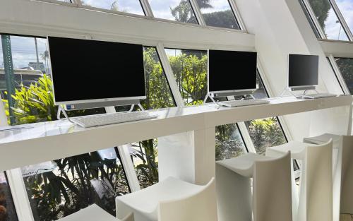 a room with three computer monitors and white chairs at Nuvo Suites Hotel - Miami Doral in Miami