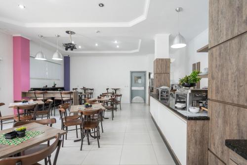 a restaurant with tables and chairs and a kitchen at Hotel Conexão in Penha