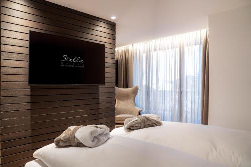 a hotel room with two beds and a flat screen tv at Stella Hotel - My Dolomites Experience in Selva di Val Gardena
